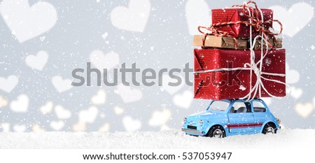 Blue retro toy car delivering heart for Valentine's day on gray background