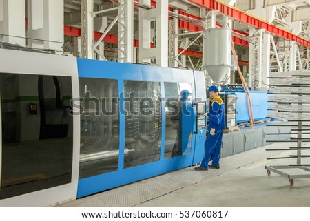 Industrial injection molding press machine for the manufacture of plastic parts using polymers in the management of worker Royalty-Free Stock Photo #537060817