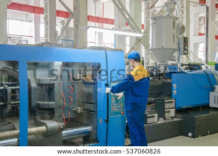Industrial injection molding press machine for the manufacture of plastic parts using polymers in the management of worker Royalty-Free Stock Photo #537060826
