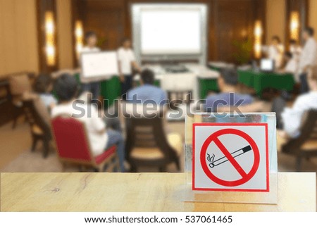 close up of no smoking sign on wooden table  over blurred meeting room  background