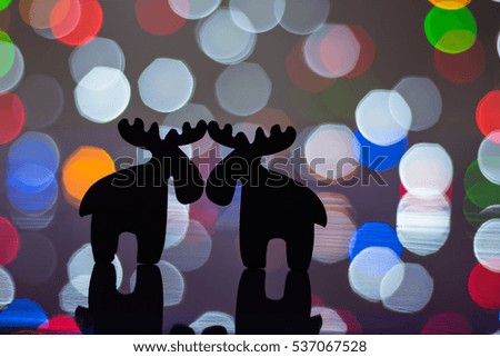 Christmas greeting card with cute reindeer silhouettes night scene over a soft focus light background