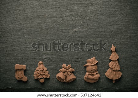 Homemade new year chocolate figures on a black slate table. Toned.