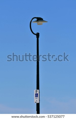 Street light on metal dark painted post with parking for disabled sign at the bottom.