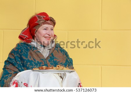 The woman in a red scarf with pancakes during the holiday Pancake week