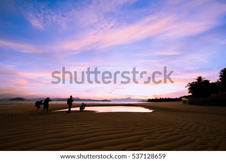  photographers in silhouette on the beach at  sunrise