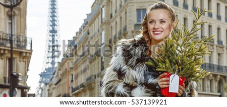 Boiling hot trendy winter in Paris. Portrait of smiling modern woman with Christmas tree in Paris, France looking into the distance