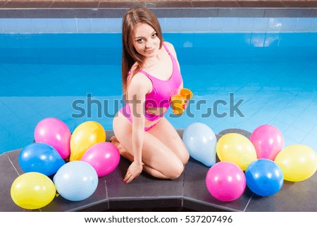 Relax, spa wellness concept. Happy woman having fun with balloons and cocktail drink alcohol. Pretty girl relaxing at swimming pool edge poolside.