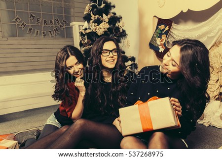 Beautiful girl opening Christmas gifts. Decorative vintage apartment.