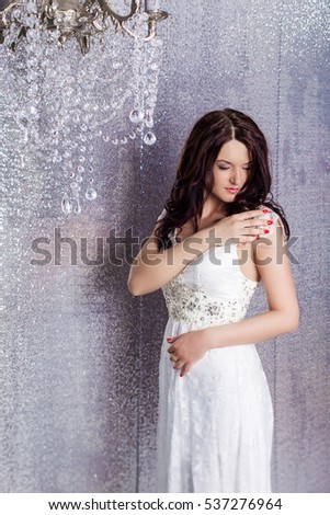 Portrait of beauty bride in white dress with classic hairstyle. Caucasian woman with curly black hair wearing a white lace wedding dress on shiny background, smiling and happy in your wedding day. 