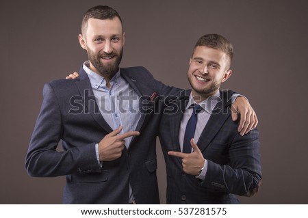 Two men in suits hugging and point the finger at each other