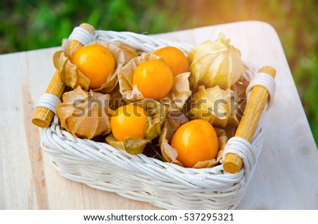 Fresh juicy group organic Cape gooseberry in basket on wood chopping Block,Physalis peruviana Royalty-Free Stock Photo #537295321