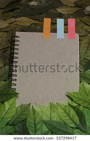 The leaves and notebook on wooden garden table.Vintage picture tone of Autumn background. can used add text message or greeting card. vignette picture