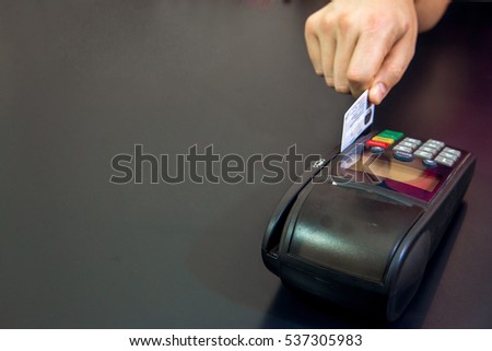 Hand Swiping Credit Card In Store. Female hands with credit card and bank terminal. Color image of a POS and credit cards.