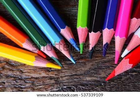 A top view image of several wooden colored pencils on a wooden surface.