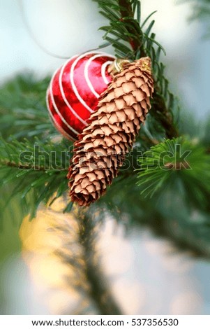 Christmas decoration on fir tree with ball and cone. Shallow focus background.