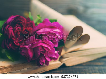 Garden pink roses and the old book on a wooden table in vintage style. Romantic image by St. Valentine's Day