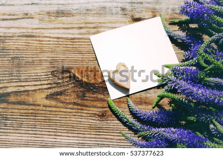 Bouquet of blue wild summer flowers,one decorative heart and white empty card for an inscription on the old wooden background