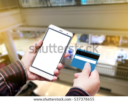Hand Hold Smart phone with Credit Card over blurred of Shopping mall.