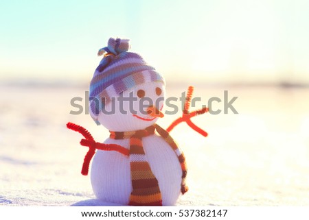 White Christmas snowman on snow. Winter sun shine on snowman. Snowman with hat in sunny christmas morning. Colorful winter background.