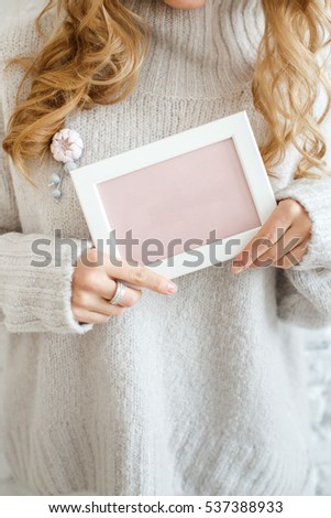 Picture in the hands of a girl in a white sweater