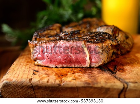 Steak with herbs and beer on a wooden background Royalty-Free Stock Photo #537393130