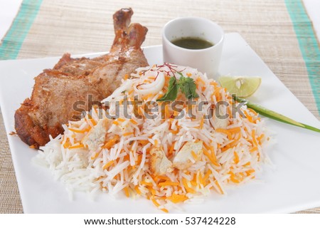 A nicely served hyderabadi chicken biryani with hint of lemon and chutney garnished with roasted fried chicken, delicious,  Royalty-Free Stock Photo #537424228