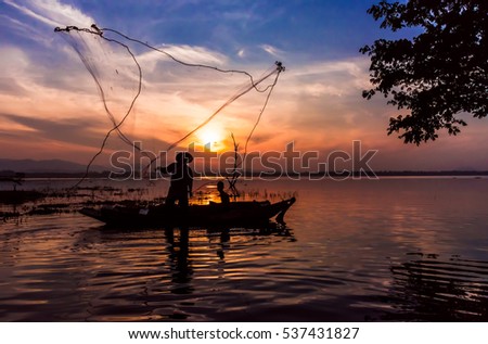 Lifestyle of Asian fisherman on wooden boat   for catching freshwater fish in reservoir in the  early morning before sunrise