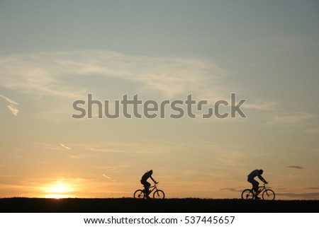 Riders cycling against sunset in silhouette with lots of negative space and dramatic sky Royalty-Free Stock Photo #537445657
