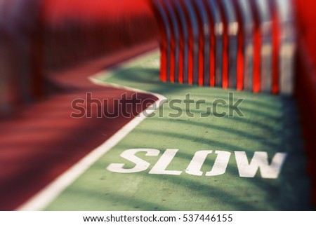Slow down bicycle sign on a cycling lane in a red pedestrian overpass tunnel 