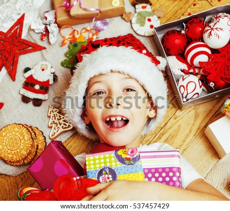 little cute kid in santas red hat with handmade gifts, toys vintage wooden, warm winter