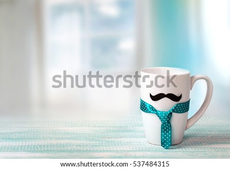 White mug on wooden table with mustache and tie indoors blue empty space background.Fathers day concept.Masculine wallpaper.  Royalty-Free Stock Photo #537484315
