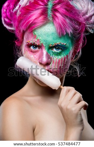 Fashion woman with creative make up eating ice cream. Young woman with pink dreads. Bizarre pink hair girl. Creative make up.  Halloween.