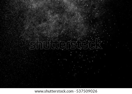 Abstract splashes of water on black background. Freeze motion of white particles. Rain, snow overlay texture