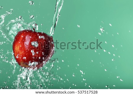 red apple in water drops on green background