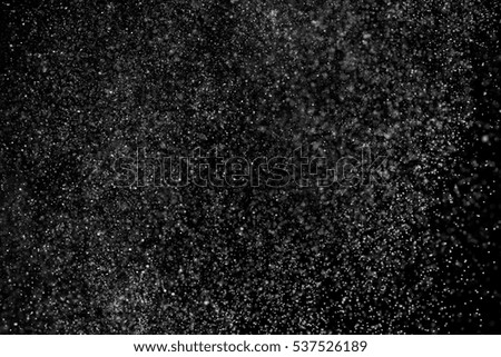 Abstract splashes of water on black background. Freeze motion of white particles. Rain, snow overlay texture