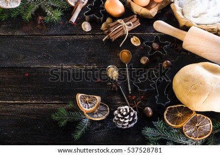 New year baking background - cones, fir tree, dough, flour, rolling pin, eggs, egg yolksover, spices, dry oranges, old dark wood background.
