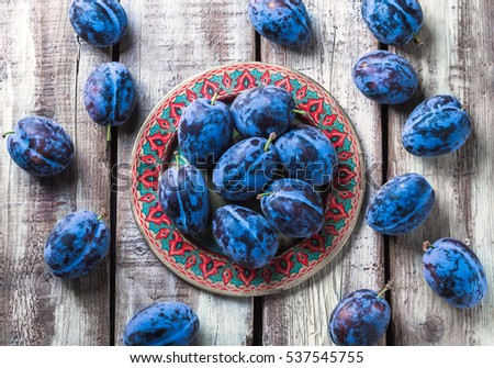 Plums overhead group on colorful plate on old rustic white wooden table in studio