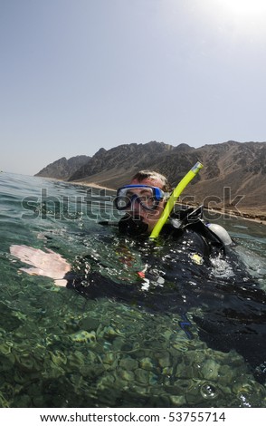 male scuba diver on surface with mountains in background