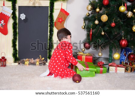 Little boy in New Year pajama  decorates a Christmas tree for New Year