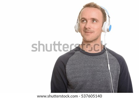 Handsome Caucasian man listening to music with headphones while thinking