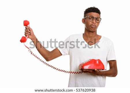 Young handsome African man looking annoyed while holding telephone