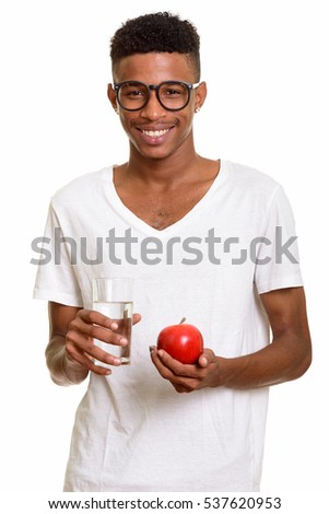 Young happy African man holding red apple and glass of water