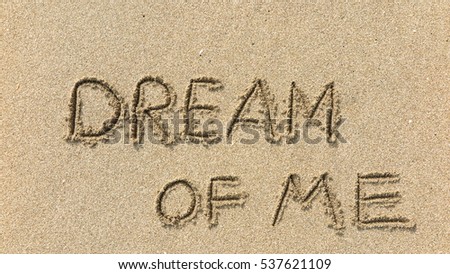 Handwriting words "DREAM OF ME" on sand of beach