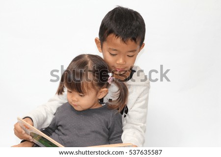 Japanese brother and sister reading a picture book (7 years old boy and 2 years old girl)