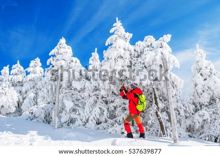 Young woman taking photo with smartphone on mountains in winter.