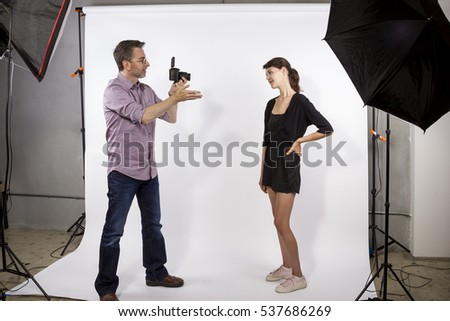 Photographer in a studio demonstrating how to light a model and take photos.  He is using softboxes with a white background. 