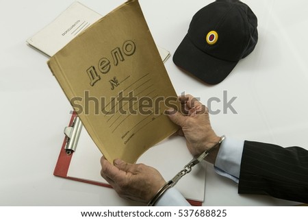 The detainee handcuffed and operational documents of the police. The inscription on the documents "Delo".