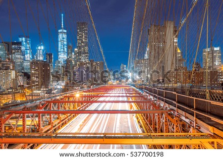 Brooklyn Bridge at night with cars traffic, view of the Financial District, Manhattan, New York City, USA