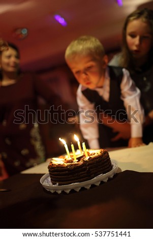 Boy blows out the candles on a cake at a birthday party