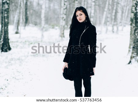 Woman winter snow nature portrait in black coat and hat